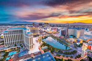 Aerial view of the Las Vegas Strip at sunset, showcasing hotels, casino lights, and replicas of landmarks under a colorful sky—a vibrant panorama flowing seamlessly like the city's intricate plumbing beneath.
